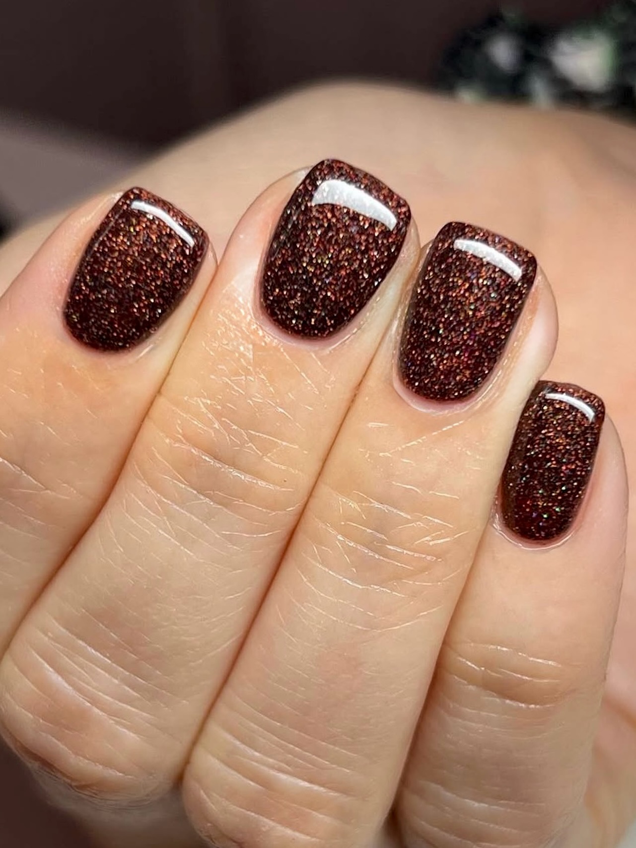 A short brown nail set with autumnal glitter specks.